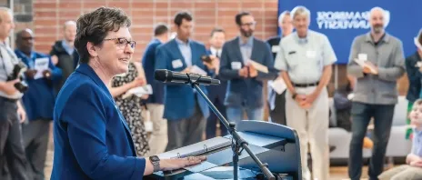 Dr. Amy Novak speaking in front of a crowd in the new Higgins Hall